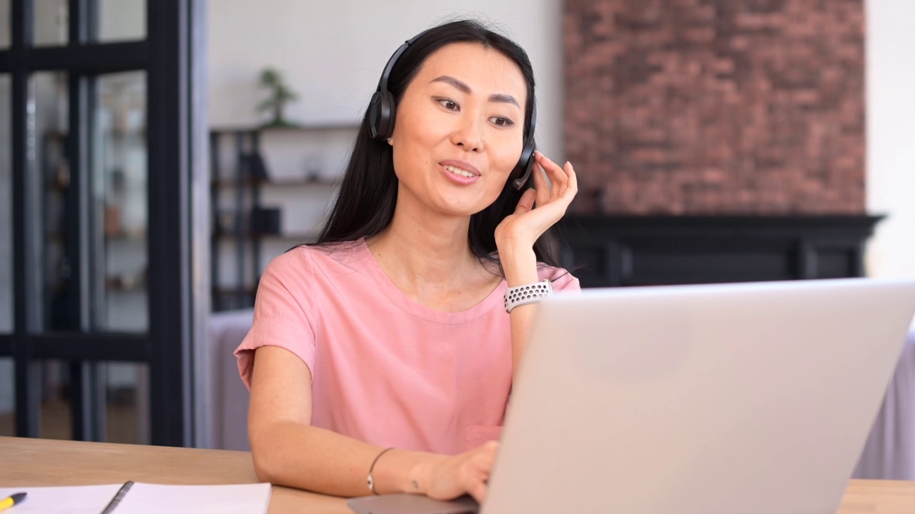 一位年轻迷人的亚洲女性正在使用笔记本电脑进行视频通话视频素材