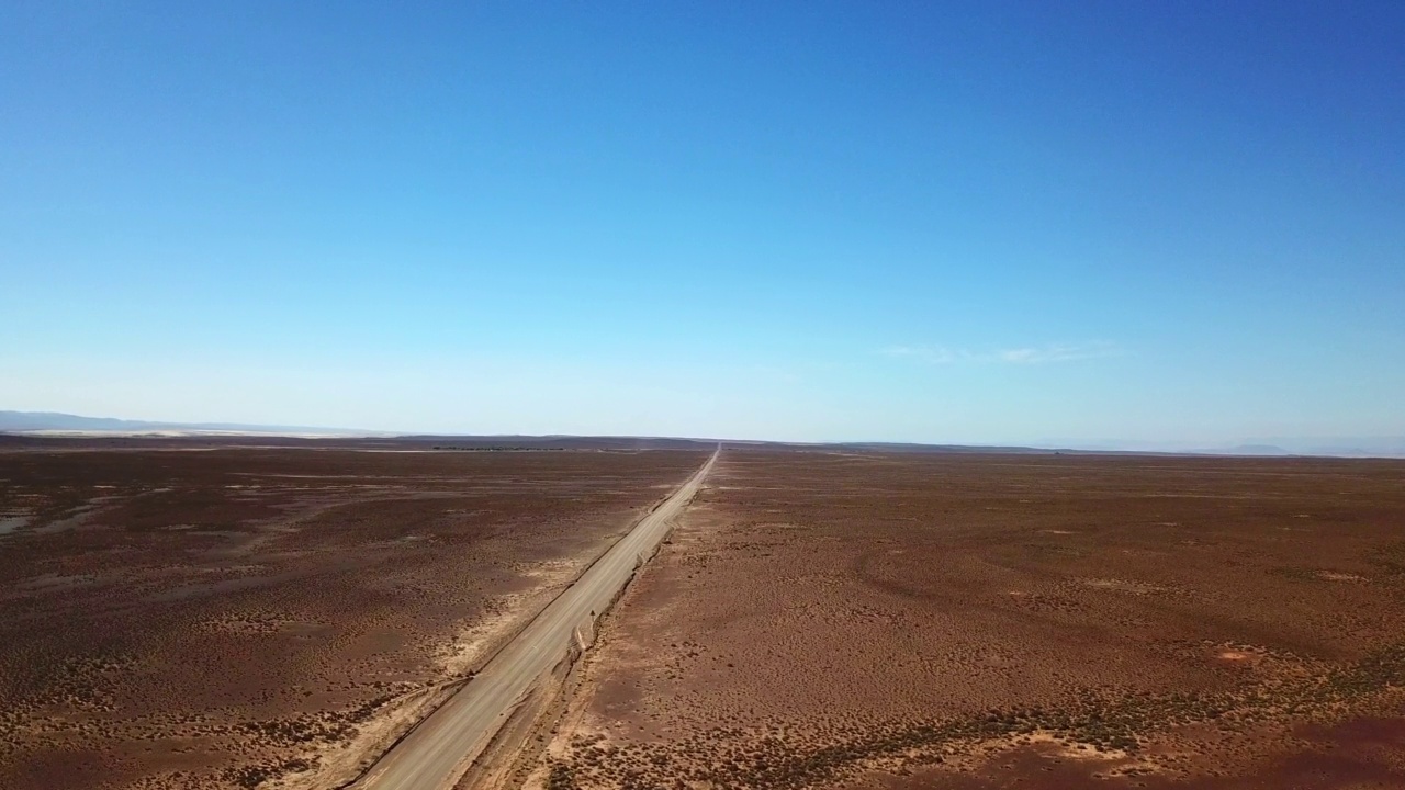 阳光明媚的日子里，半干的土地包围着一条空旷的道路。穿过卡鲁荒野的一条很长的路视频素材