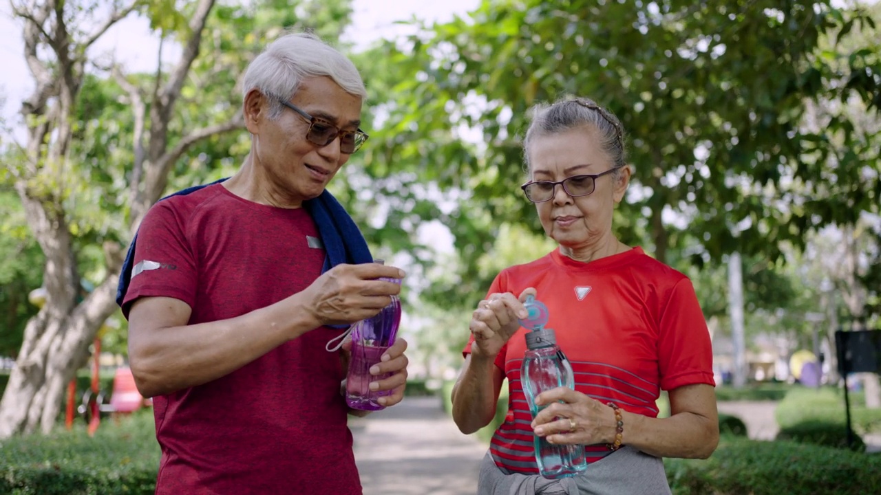 两个老年人在公园锻炼后喝水视频素材