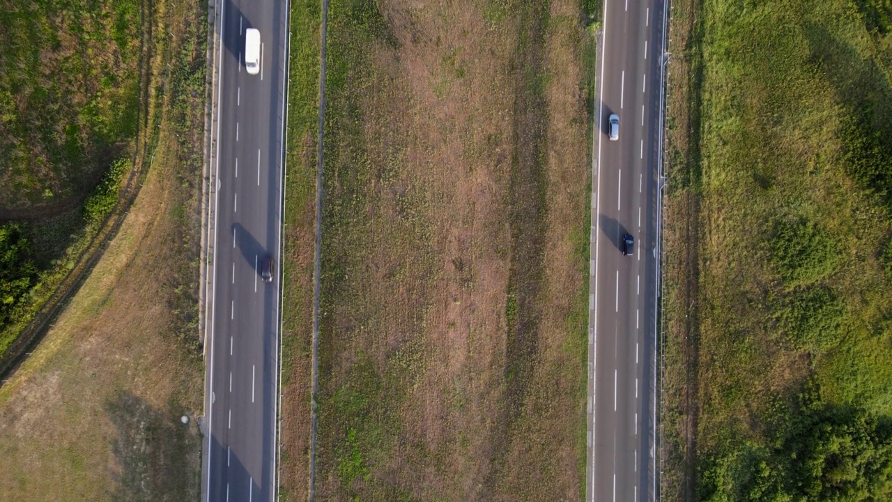 夏天，汽车和卡车在公路上驶过乡间田野的鸟瞰图。无人机拍摄与流畅的相机运动视频下载