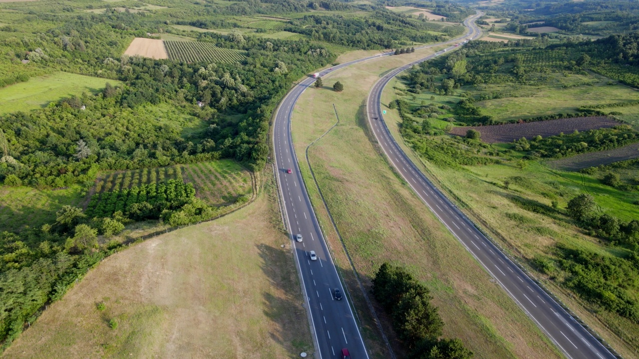 高速公路在日落时分。汽车和卡车在公路上驶过乡间田野视频下载