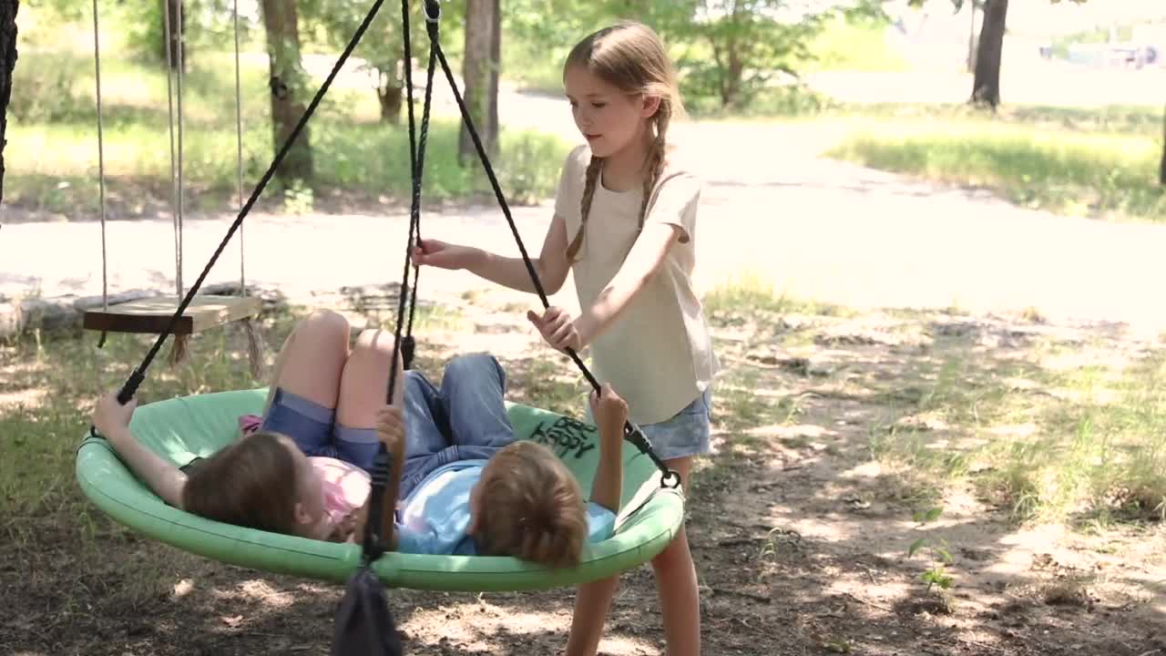 年幼的兄弟姐妹一起在户外荡秋千，欢笑着视频素材