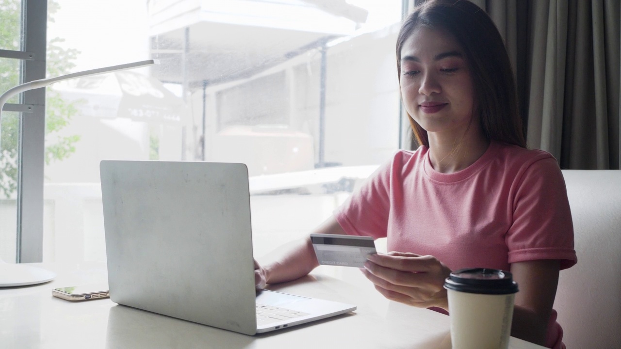 快乐的亚洲女人用她的智能手机和信用卡买东西。视频素材