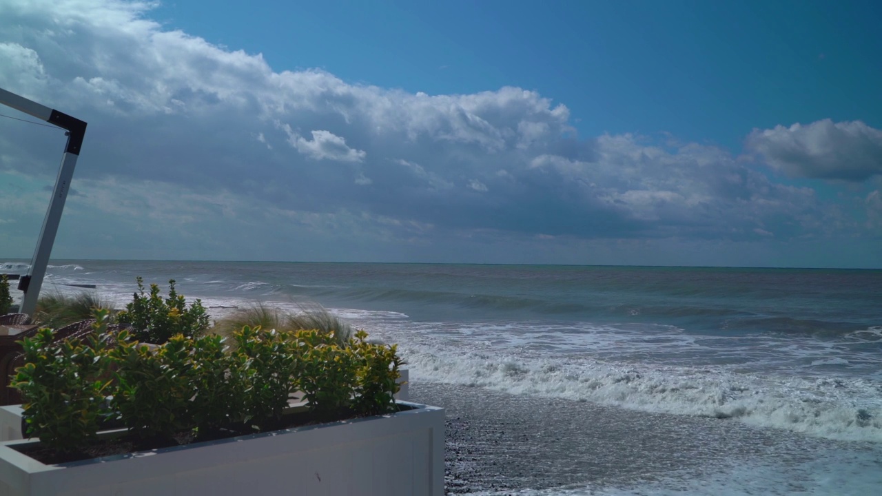 现代酒店露台与夏季咖啡馆的背景海滩和蓝色的大海与波浪。从开放式餐厅到海景的视野。视频素材