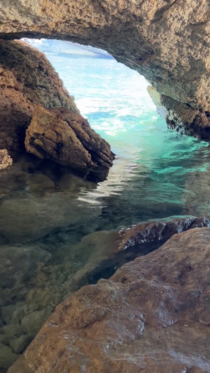 清澈的蓝色海水在洞穴的岩石间流动。视频素材