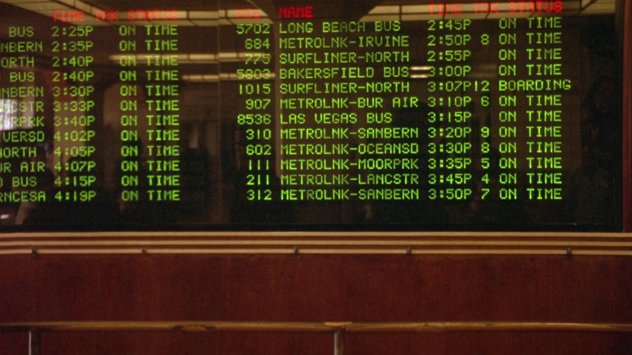 联合车站电子列车时刻表的中角度。见绿色文字的抵港及离港名单。地点是加利福尼亚和拉斯维加斯。见人走在板子前，停下来查看时刻表视频素材