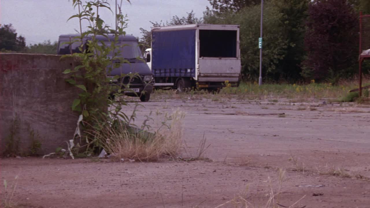 中等角度的奔驰短跑货车右转到乡村道路或住宅街道。在背景中看到废弃的运输卡车和树木视频素材