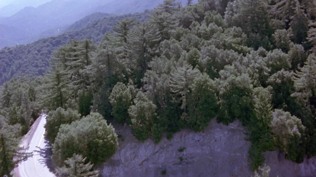 长满常青树的山腰。看到蜿蜒的道路沿着山的一侧运行视频素材