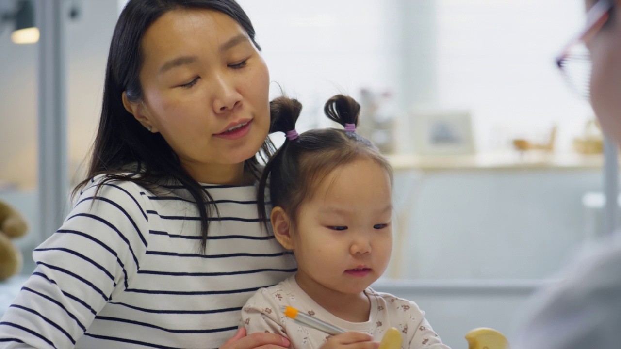 亚洲妇女带孩子与儿科医生交谈视频素材