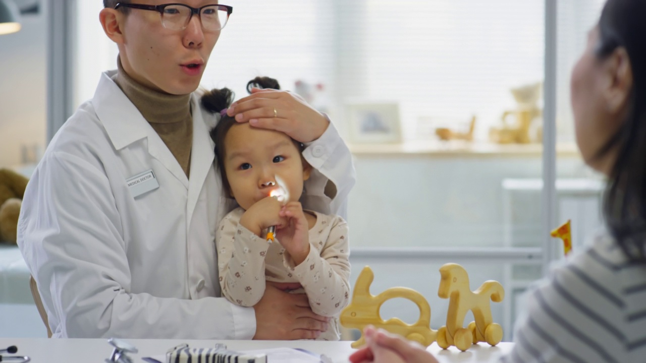 亚洲儿科医生坐在小女孩和她的妈妈说话视频素材