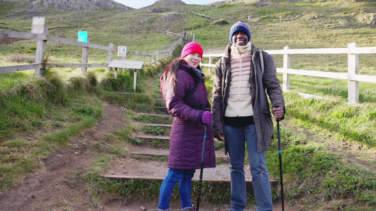 在英国多塞特郡，一对穿着保暖衣服，拄着登山杖的幸福夫妇视频素材