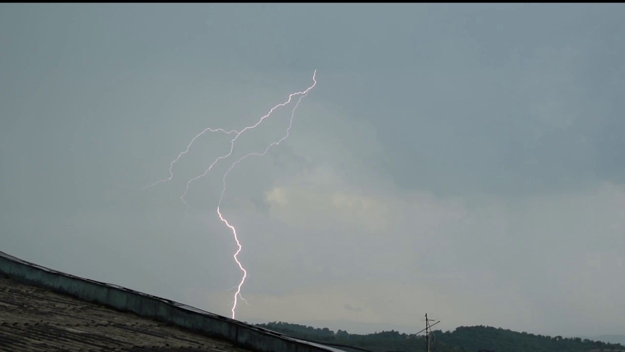 一组美丽的闪电击中城市，高清股票视频的真正的闪电和雨滴在树叶，和多云的天空。视频素材