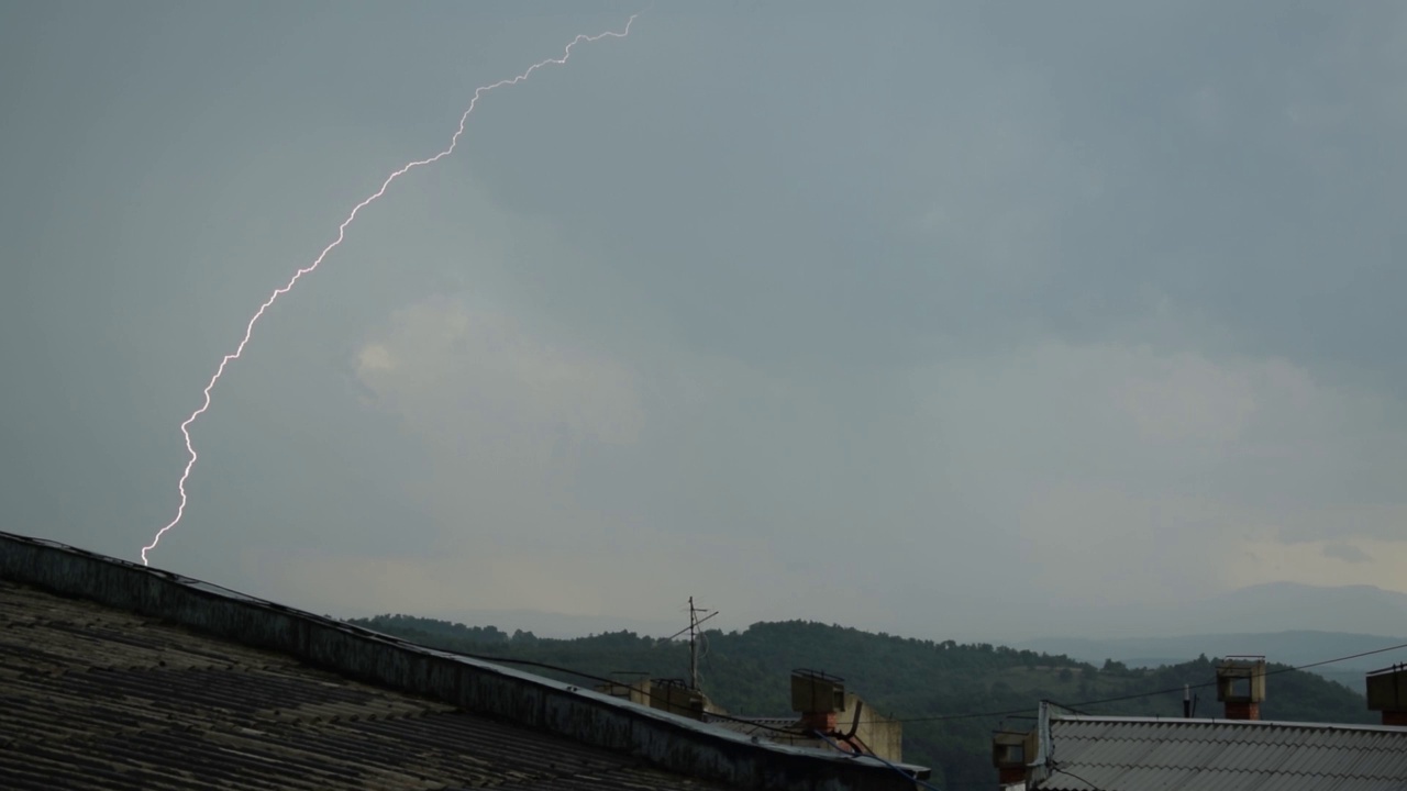 一组美丽的闪电击中城市，高清股票视频的真正的闪电和雨滴在树叶，和多云的天空。视频素材