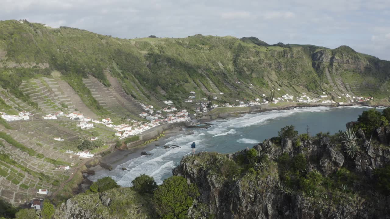 一个人在海边的悬崖上俯瞰海岸线的鸟瞰图。视频素材