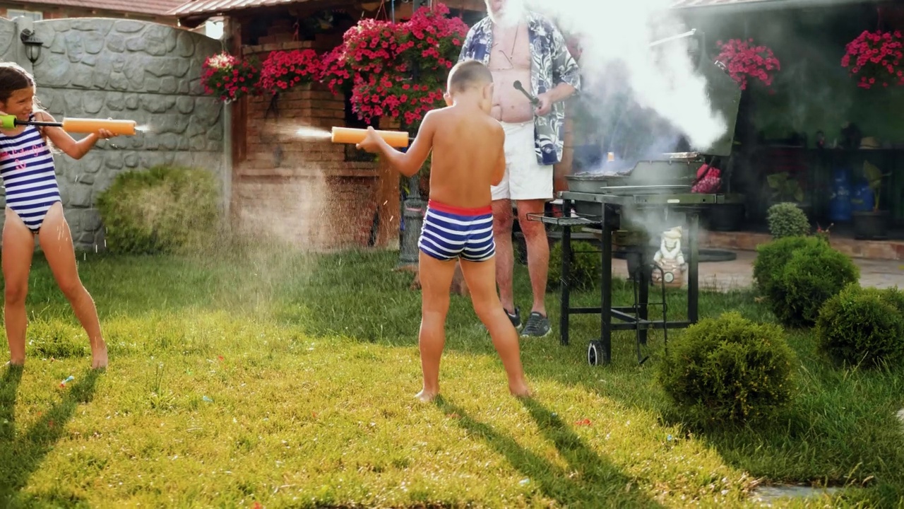 炎炎夏日，孙儿们在后院用水枪泼水嬉戏视频素材