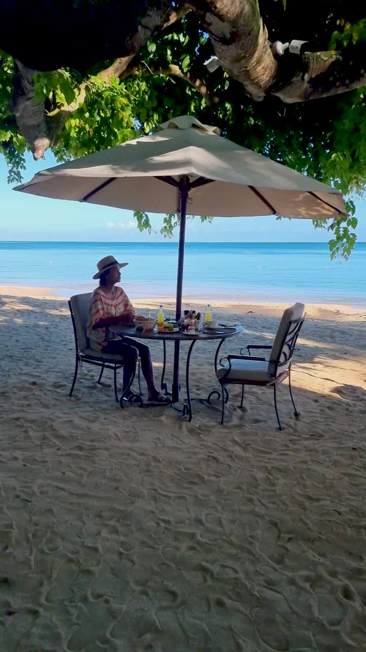 一位在毛里求斯海滩上吃早餐的妇女视频素材