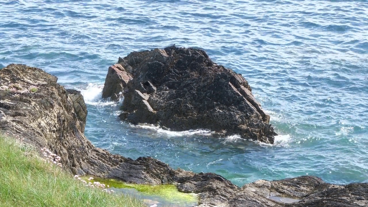 一块石头和海水，4k视频。海景，阳光明媚，天气温暖。手持视频。视频素材