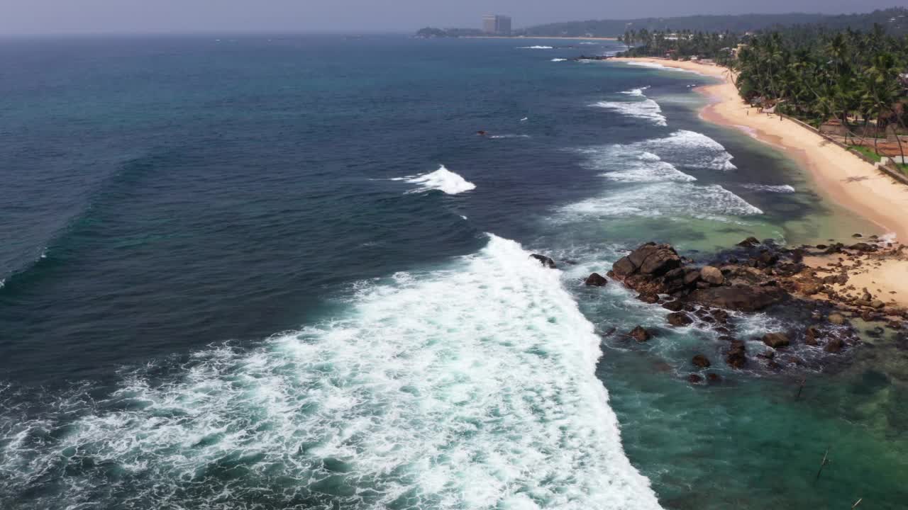 4K广角无人机拍摄的斯里兰卡海滩，海浪翻滚，城市远处视频素材