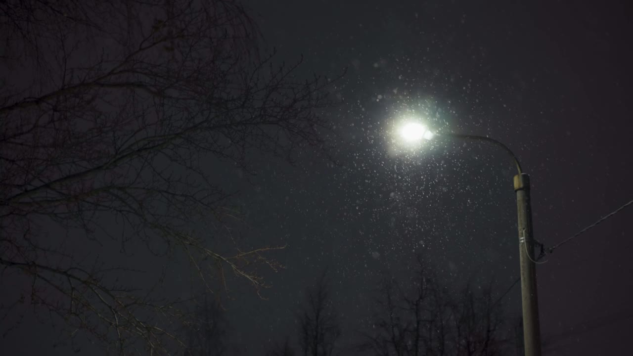 大雪纷飞的城市，雪花在夜晚映衬着一盏灯笼。晚上的街道。视频素材