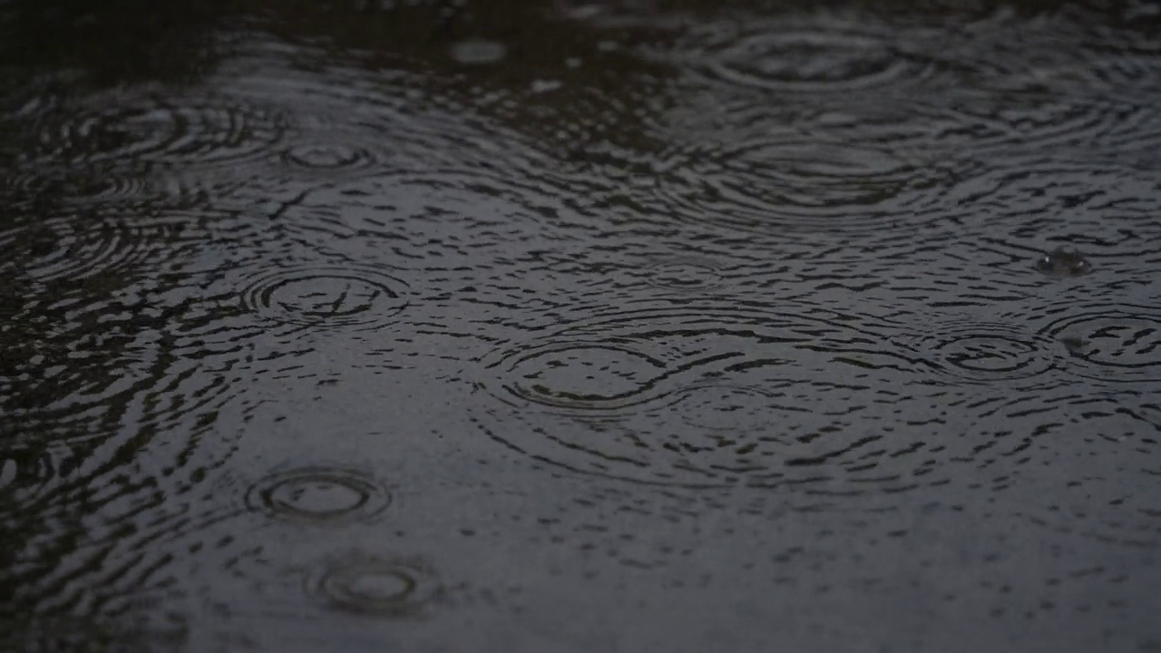 4K慢动作视频，下雨天的水坑上泛起阵阵涟漪。视频素材