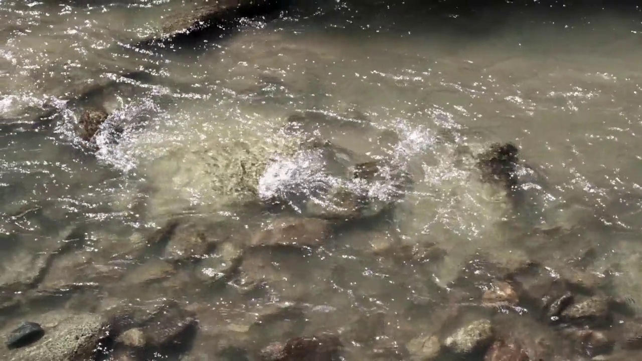 山河水面。透明的小溪流水背景特写。湍急的水流穿过石头视频素材