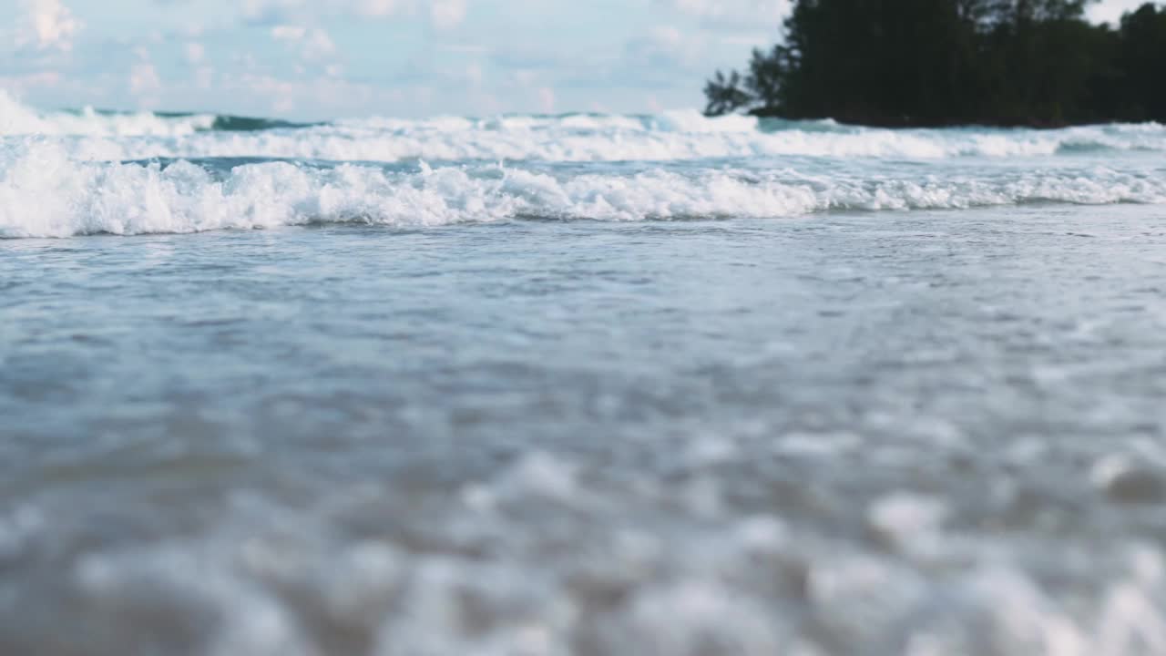 夏天的海滩、海沙和天空。海滩遇到深蓝色的海水和泡沫的波浪视频素材