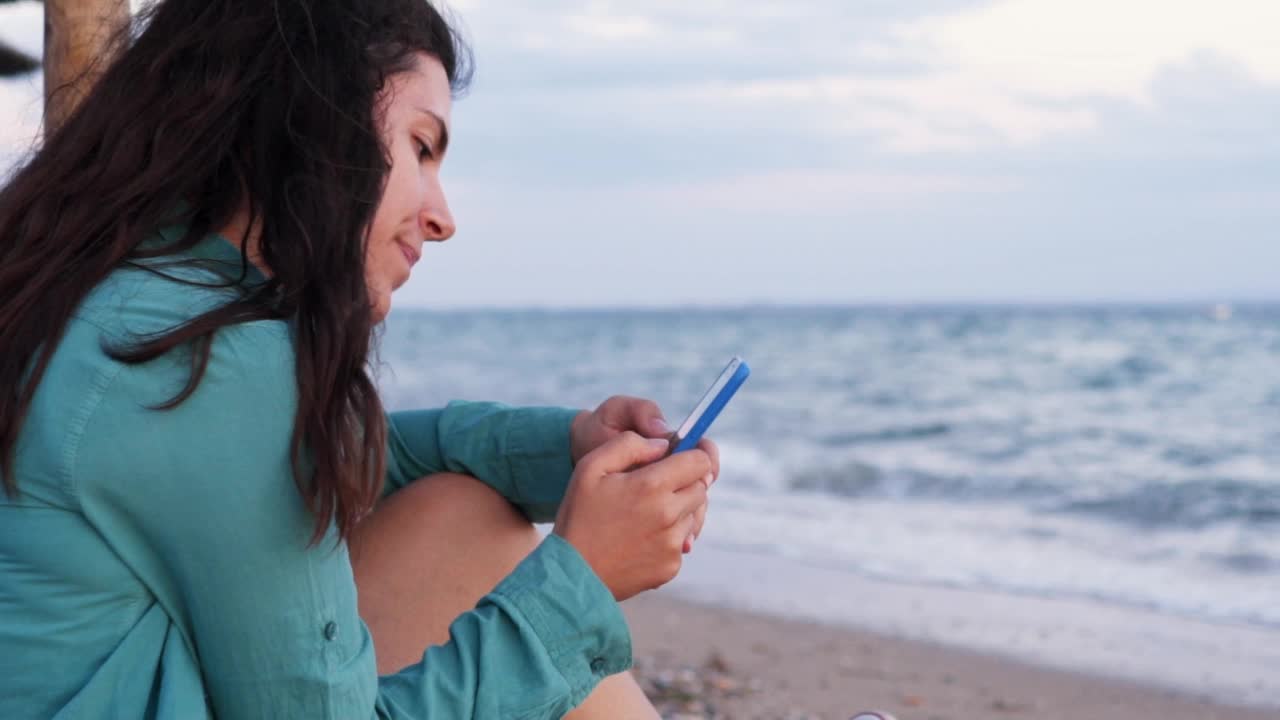 女人在海滩上使用智能手机视频素材