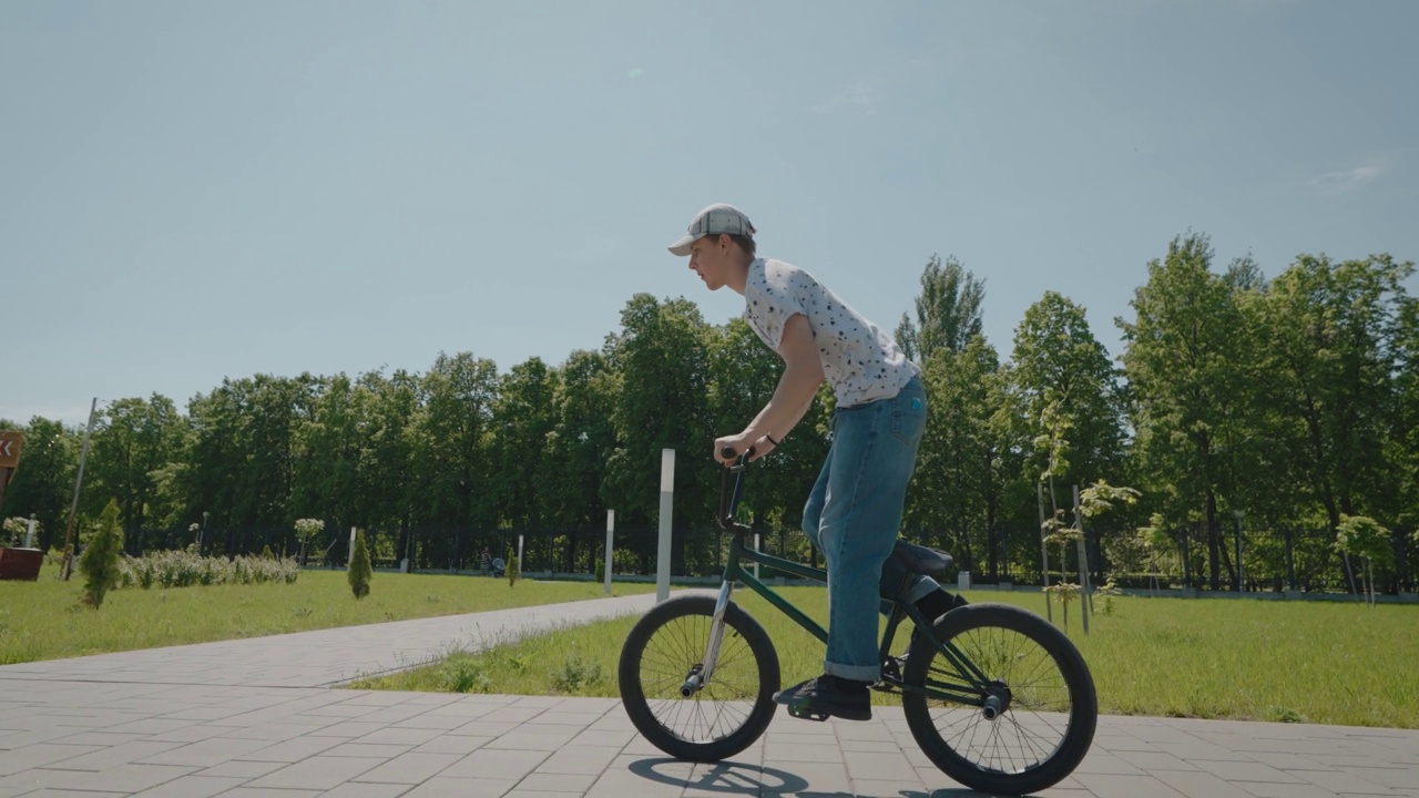 城市里的小轮车极限自行车手。一名男子在城市公园里骑自行车，表演跳跃和特技。视频素材