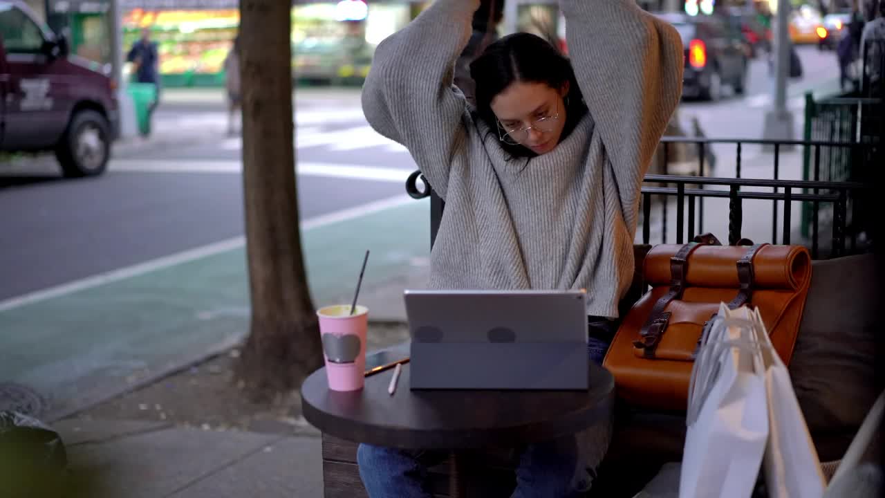 迷人的潮女孩戴着蓝牙耳机，通过触摸板和智能手机设备在线听音乐视频素材