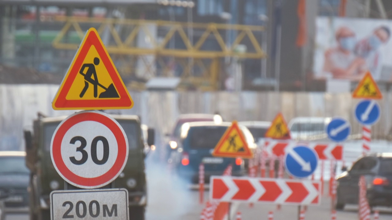 道路工程警告交通标志的建筑工程在城市街道和缓慢移动的汽车视频素材