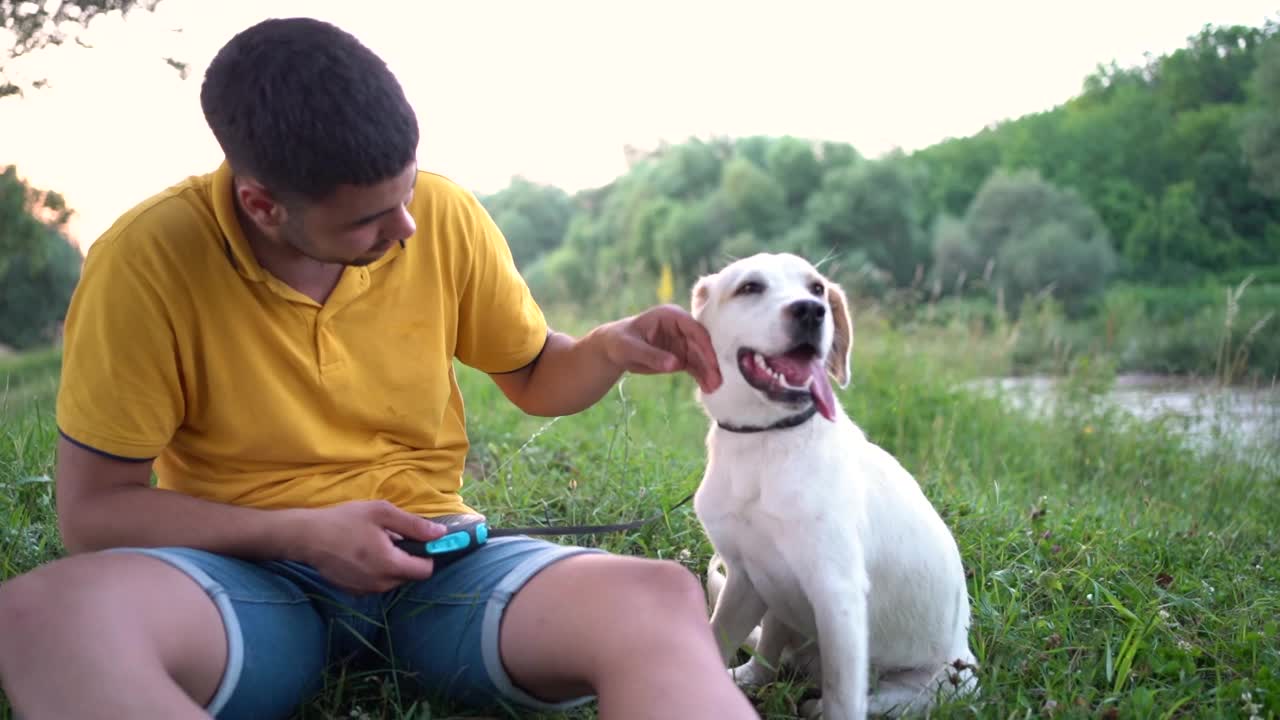 一个年轻人和他的狗在大自然中放松视频素材