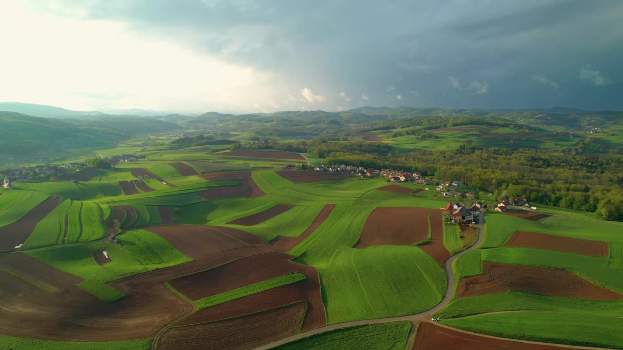 鸟瞰美丽的丘陵乡村，有草地、田野和小村庄视频素材