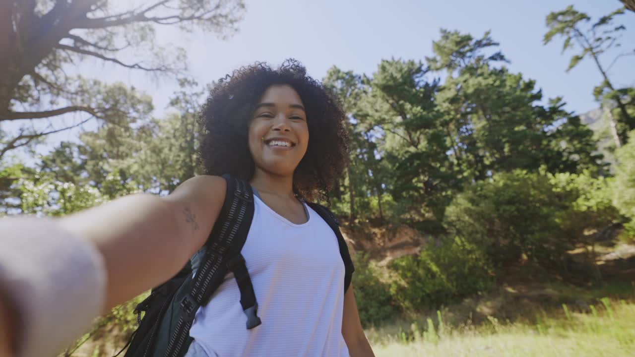 一名女性徒步旅行时拍摄自拍照视频，拍摄森林风景。微笑积极的女人徒步穿越高山，为社交媒体或博客拍摄照片视频素材