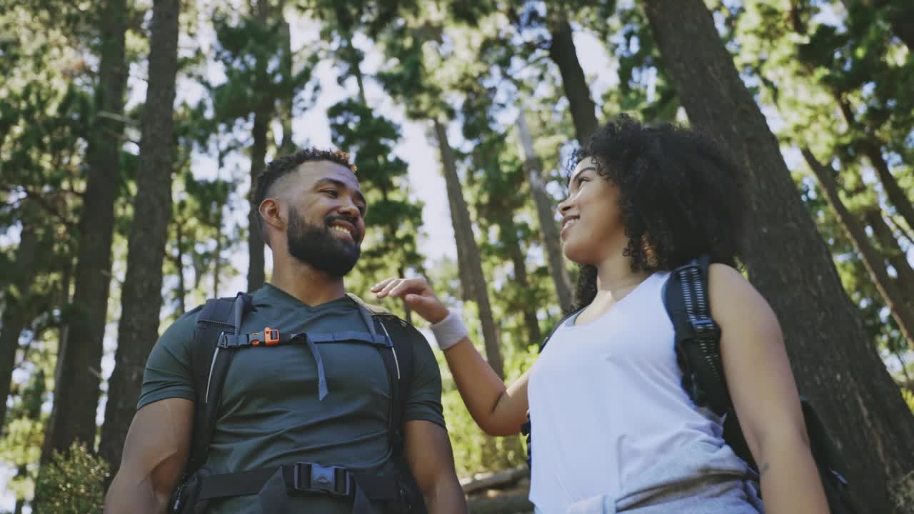 一对情侣一起站在森林里，环顾四周的风景。男人和女人徒步旅行，欣赏树林的景色。男男女女背着双肩包在自然环境中度假视频素材