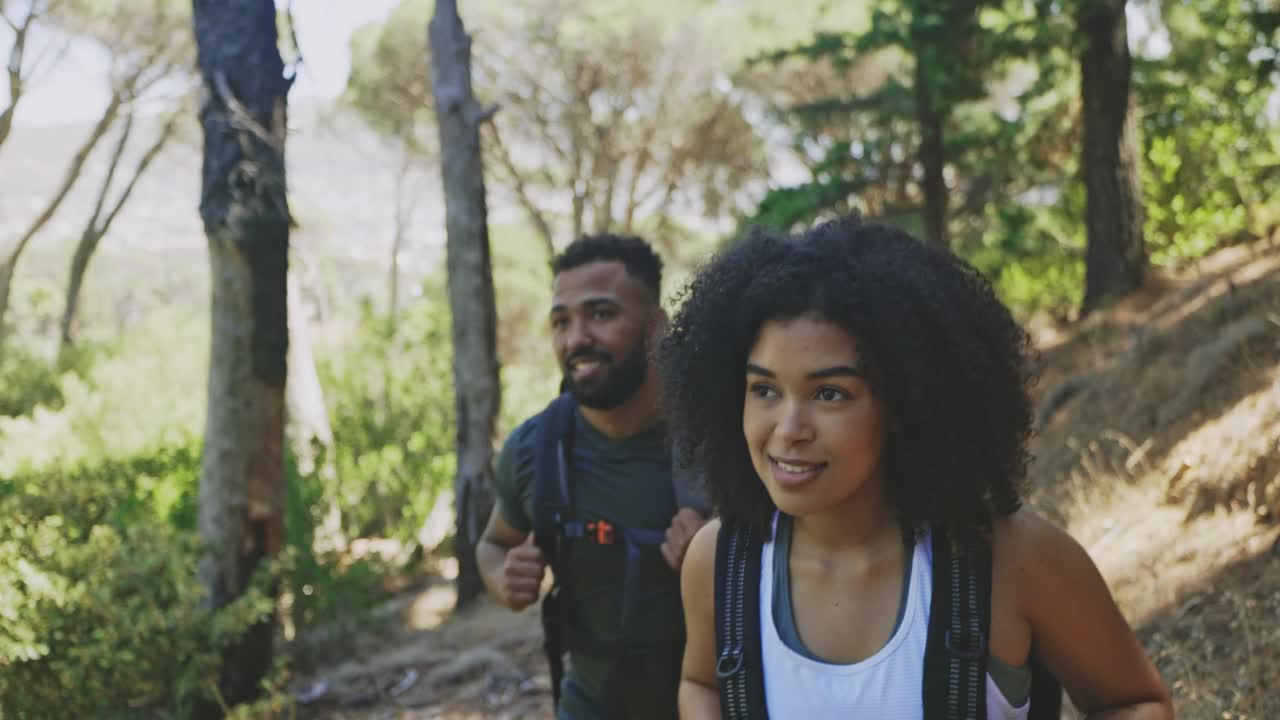 一对夫妇在度假时一起登山。两个年轻健康的徒步旅行者在森林里微笑着享受大自然。活跃的男女游客散步和探索森林视频素材