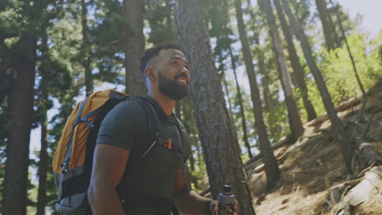 一名年轻男子在森林里徒步旅行时，在休息时用瓶子喝水。徒步旅行和探索自然的同时享受在森林里的冒险视频素材