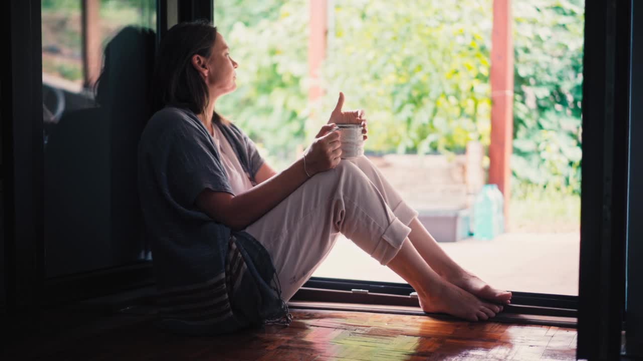 一位年轻的成年女性坐在露台上享受她的早茶视频素材