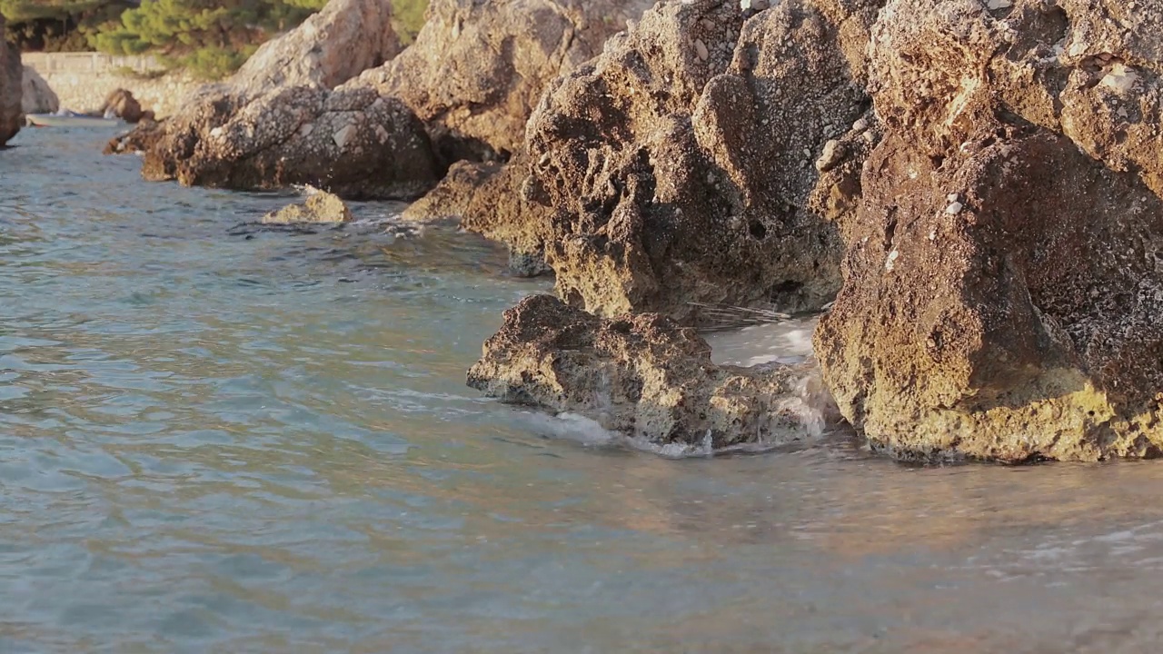 日落时海浪和岩石海岸。视频素材