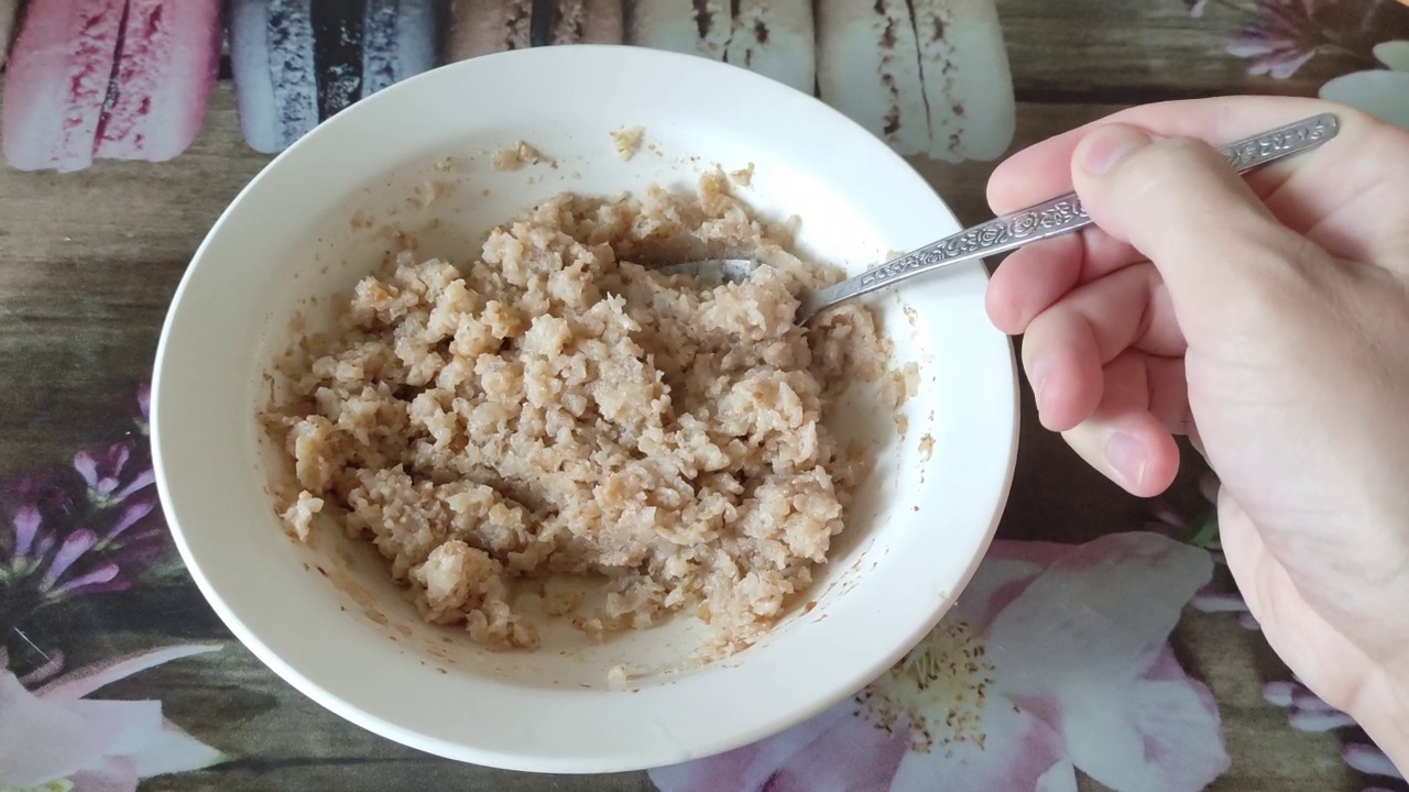 一位陌生男子用勺子搅拌荞麦粥，冷却食物视频素材