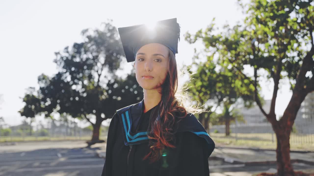 一名年轻的女学生在毕业典礼上看起来很开心，她站在大学校园外面。微笑着毕业，准备在校园里接受毕业证书视频素材