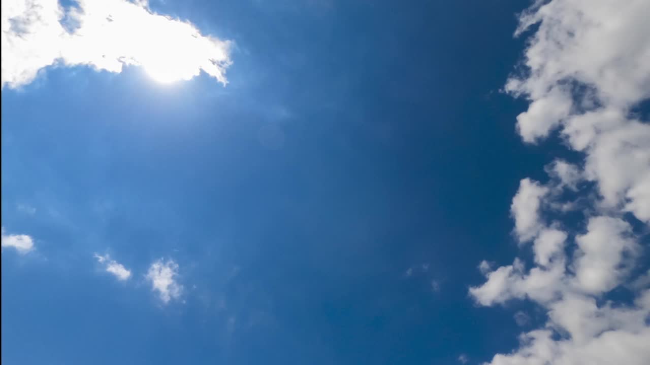 明亮的太阳在蓝色的天空中闪耀。朵朵白云在太阳的映照下飞快地飞翔。视图从下面。间隔拍摄。视频素材