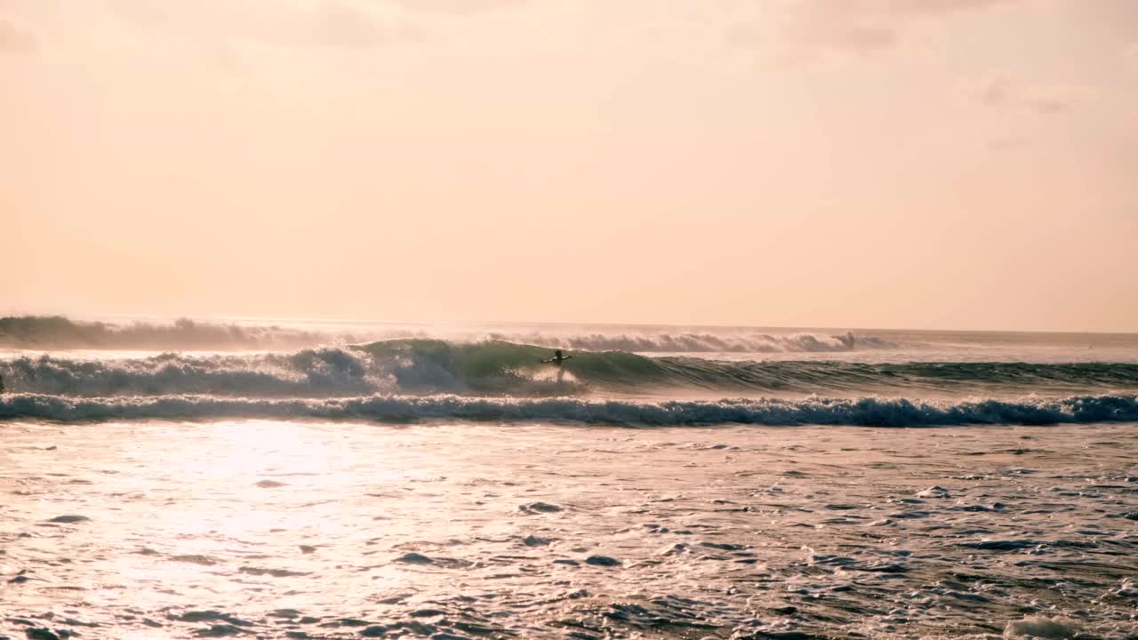 极限运动。海洋里的冲浪者。晚上上网。许多人在夕阳的映衬下，用冲浪板在海浪上冲浪。印尼巴厘岛视频素材