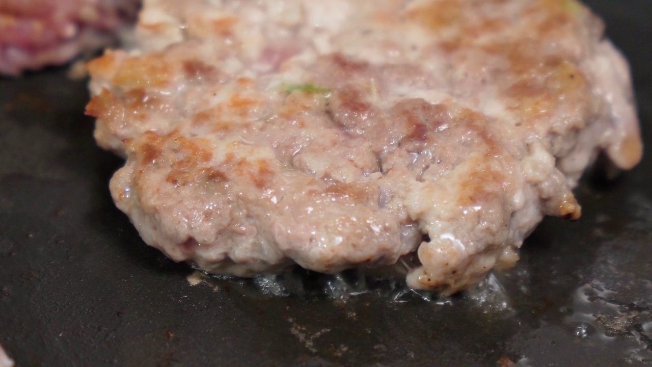 在煎锅里烤牛肉饼的特写。烹饪过程。有选择性的重点视频素材