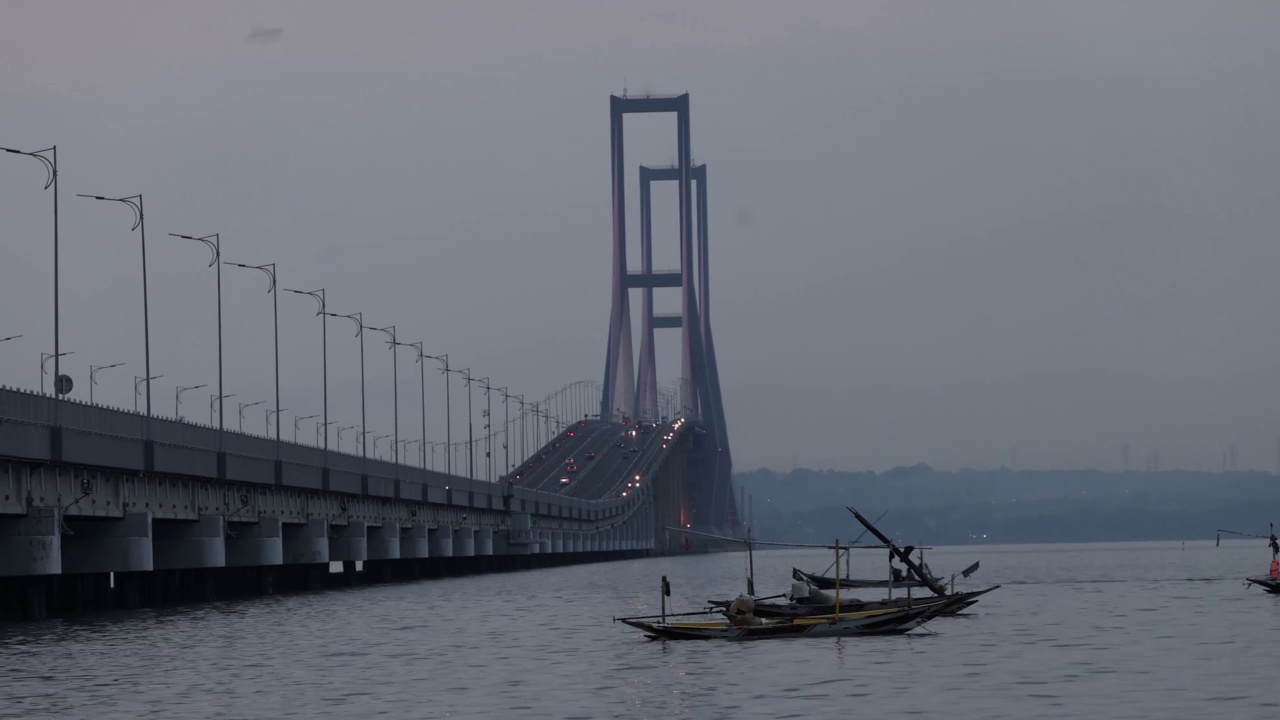 以苏拉马杜大桥为背景的渔船在爪哇海中穿梭。印尼连接爪哇岛和马杜拉岛的最长大桥视频素材