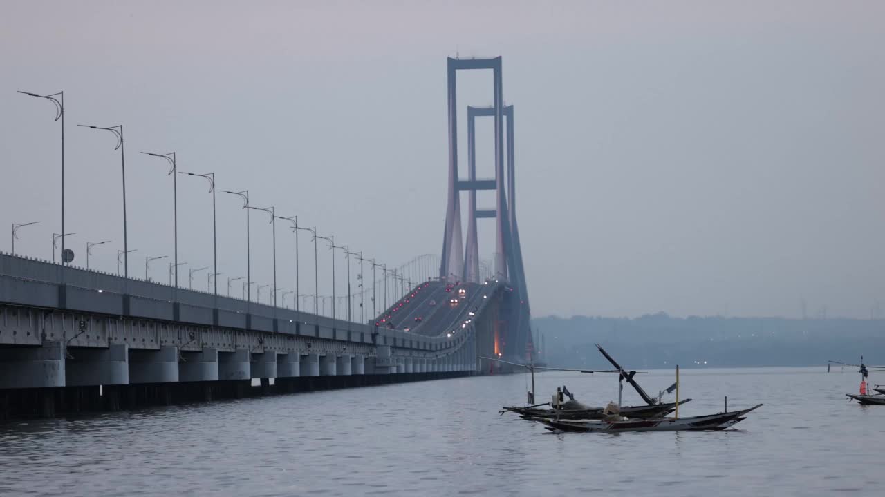 以苏拉马杜大桥为背景的渔船在爪哇海中穿梭。印尼连接爪哇岛和马杜拉岛的最长大桥视频素材