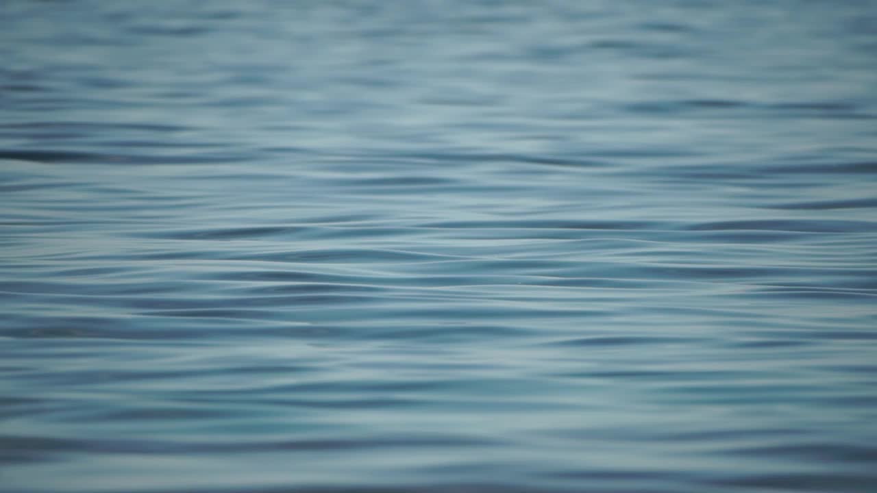 抽象海洋夏季海洋日落自然背景。小波浪水面上的运动模糊与金色的散景灯从太阳。度假、度假和休闲的概念。慢动作视频素材