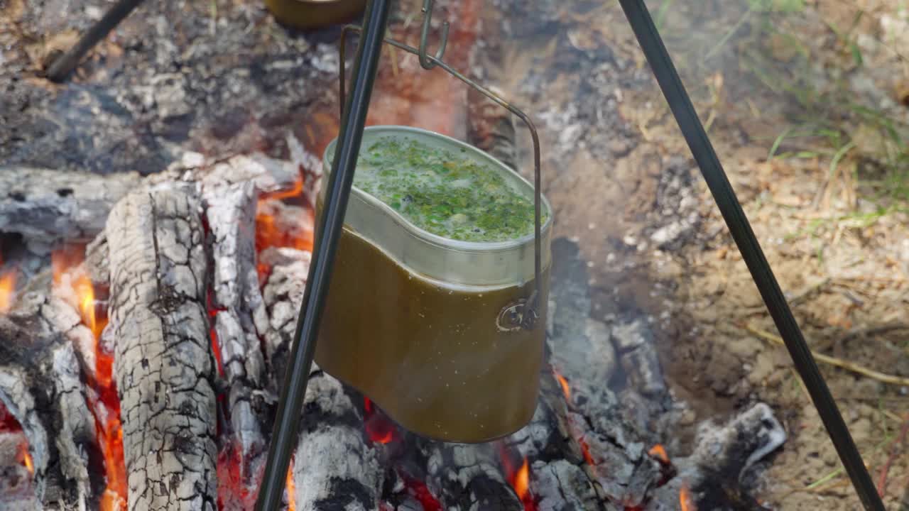 登山时在篝火上做饭，汤是在锅里煮的，近距离看火，在一个美丽的夏天的森林里视频素材