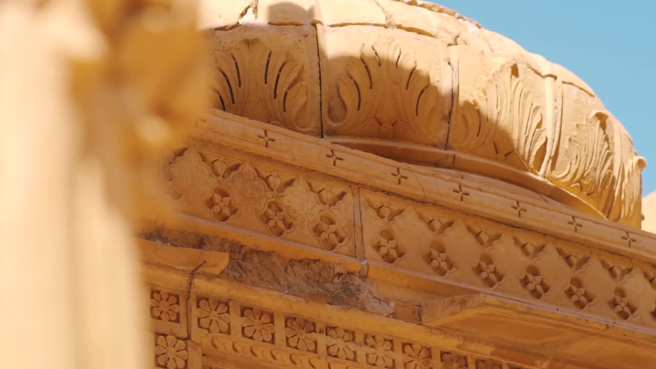 在印度拉贾斯坦邦的Jaisalmer的Bada Bagh的chattri圆顶纪念碑顶部雕刻的特写镜头。建筑顶部的雕刻是用砂岩做成的。穹顶上的古老雕刻。视频素材