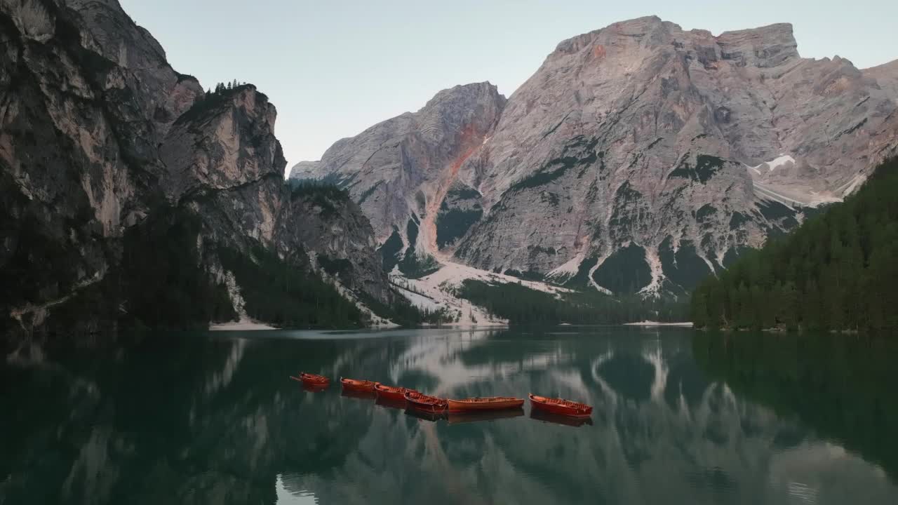 无人机查看最美丽的拉戈迪布雷斯的日出场景，也被称为Pragser Wildsee。白云石山脉,意大利。飞出碧绿平静的水面，船在生涩。视频素材