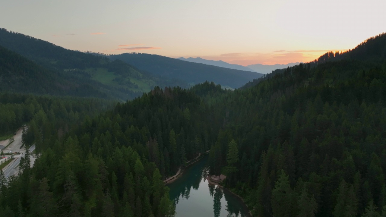 无人机查看最美丽的拉戈迪布雷斯的日出场景，也被称为Pragser Wildsee。白云石山脉,意大利。飞出碧绿平静的水面，船在生涩。视频素材